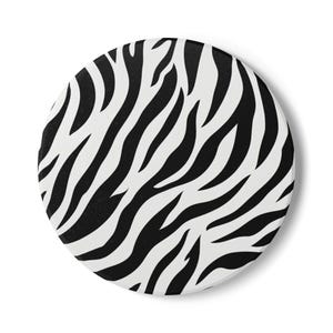 May include: A circular coaster featuring a high-contrast black and white zebra stripe pattern. The design consists of organic, flowing lines that cover the entire surface of the round object, creating a bold, repeating animal-inspired graphic print.