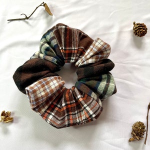 May include: A brown, orange, white and blue plaid scrunchie made from fabric.