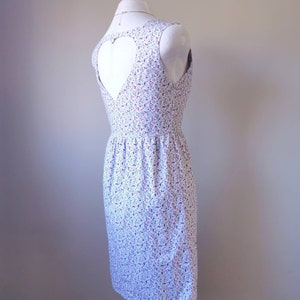 Peut inclure: Une robe blanche &agrave; imprim&eacute; floral avec une d&eacute;coupe en forme de c&oelig;ur dans le dos.