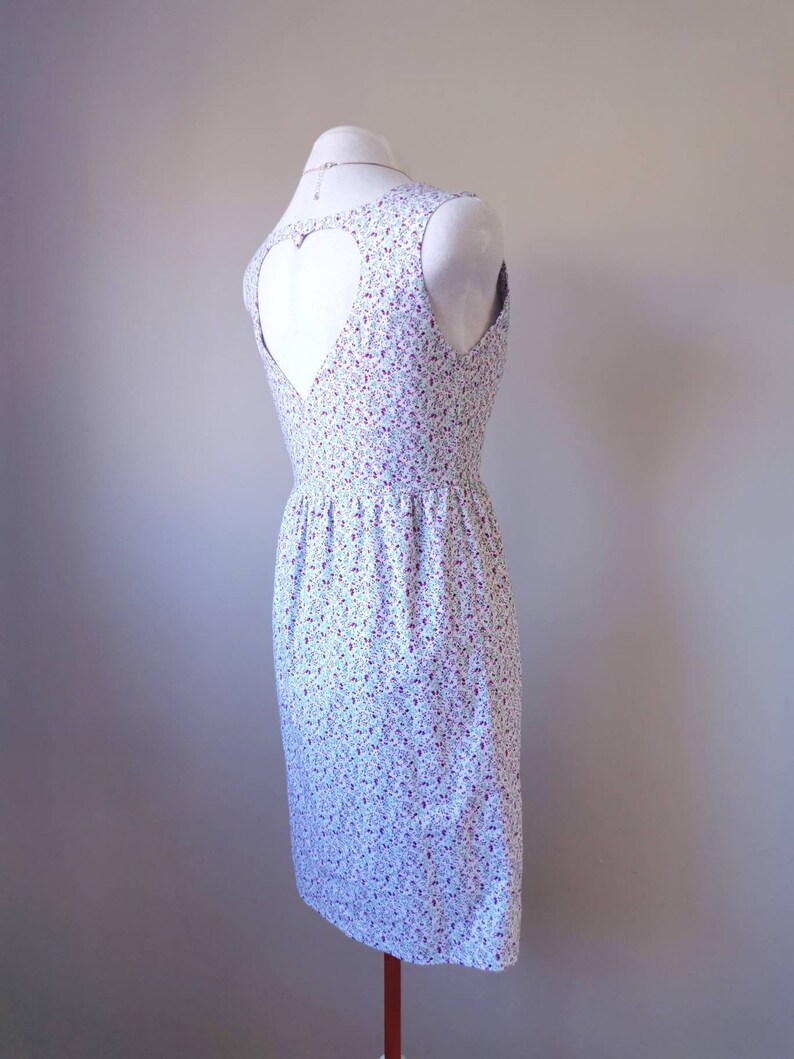Peut inclure: Une robe blanche &agrave; imprim&eacute; floral avec une d&eacute;coupe en forme de c&oelig;ur dans le dos.