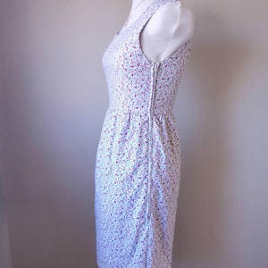 Peut inclure: Une robe blanche sans manches avec un petit imprim&eacute; floral dans les tons rose et bleu. La robe a un corsage ajust&eacute; et une jupe l&eacute;g&egrave;rement &eacute;vas&eacute;e.