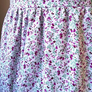 Peut inclure: Tissu blanc avec un petit motif floral violet. Le tissu est fronc&eacute; en haut, cr&eacute;ant un volant.