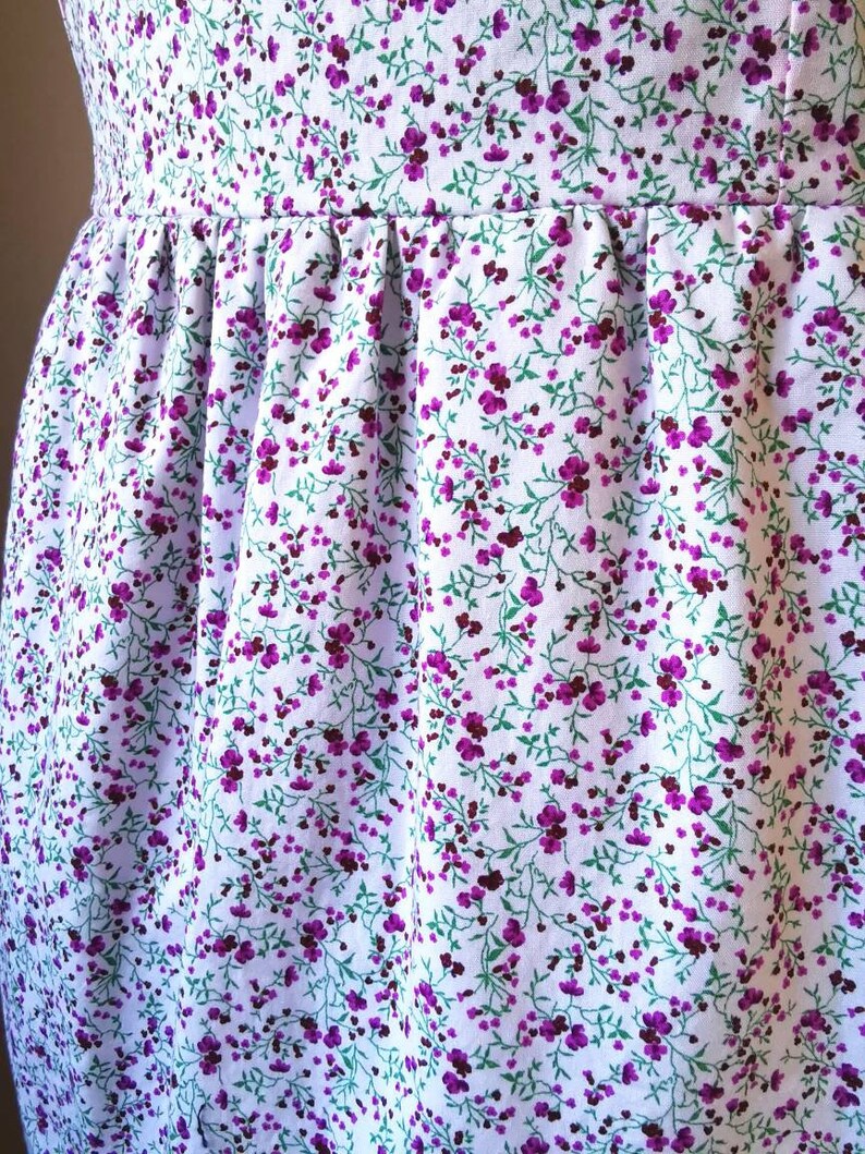 Peut inclure: Tissu blanc avec un petit motif floral violet. Le tissu est fronc&eacute; en haut, cr&eacute;ant un volant.