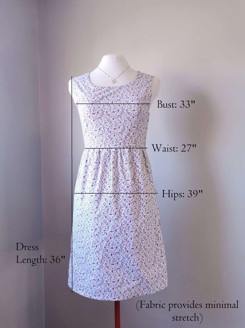 Peut inclure: Une robe blanche &agrave; petit imprim&eacute; floral dans les tons violet et rose. La robe a un col rond, des manches courtes et un corsage ajust&eacute; qui s'&eacute;vase en une jupe. La robe mesure 91 cm de long, 84 cm de tour de poitrine, 69 cm de tour de taille et 99 cm de tour de hanches. Le tissu a une &eacute;lasticit&eacute; minimale.