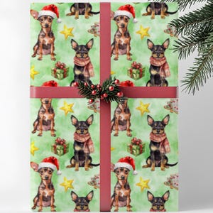 May include: Christmas-themed wrapping paper featuring a repeating pattern of small dogs wearing Santa hats and scarves, along with gift boxes and stars on a green background. The wrapped gift is tied with a red ribbon and decorated with a sprig of berries.
