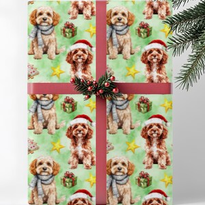 May include: Christmas-themed wrapping paper featuring a repeating pattern of adorable dogs wearing Santa hats and scarves. The background is a light green with yellow stars and gift boxes. The paper is wrapped with a red ribbon and a sprig of greenery.
