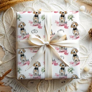May include: White gift wrap with a repeating pattern of a dog wearing a bow tie and holding a bouquet of flowers. The text "Forever" and "Love" are on pink banners. The gift wrap is tied with a white satin ribbon.