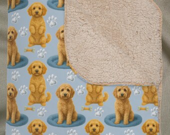 以下が含まれることがあります： ゴールデンレトリバーの子犬、足跡、骨の繰り返し模様が特徴の、明るい青色のブランケット。ブランケットの裏側には、柔らかいベージュのシェルパの裏地が付いています。ブランケットは折りたたまれており、模様のある面が見えています。