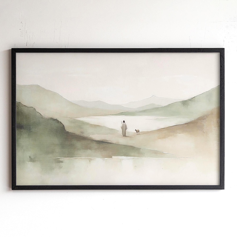 May include: A framed watercolor print depicting a serene landscape with muted green and beige tones. A figure in a robe walks with a small dog towards a body of water, with rolling hills and mountains in the background. The frame is black.