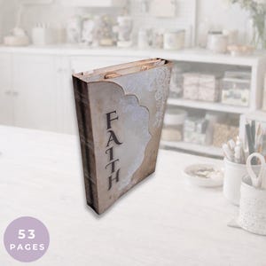 Puede incluir: Una caja decorativa con forma de libro de estilo vintage con la palabra "FAITH" impresa verticalmente en la parte delantera. La caja tiene un aspecto envejecido y desgastado con un fondo color crema y detalles florales. Contiene 53 páginas.