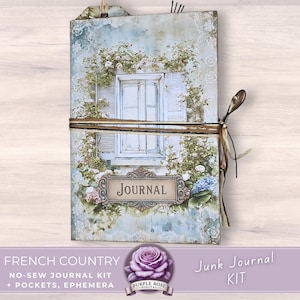 Może przedstawiać: Dziennik w stylu vintage z kwiatowym i okiennym wzorem. Okładka przedstawia białe okno z okiennicami, otoczone białymi kwiatami i zielenią. Słowo "JOURNAL" jest wyświetlane na ozdobnej etykiecie. Dziennik jest związany sznurkiem.