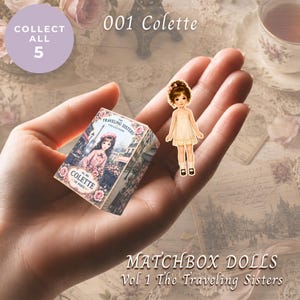 May include: A miniature matchbox labeled 001 Colette The Traveling Sisters Collection with a floral design and a small paper doll figure wearing a cream dress and dark shoes. The text reads 001 Colette, Collect All 5, and Matchbox Dolls Vol 1 The Traveling Sisters.