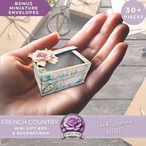 May include: A miniature gift box with a floral design, held in a hand. The box has a clear top and is decorated with a pink flower and bow. Text on the box reads "Journal". The image also includes text that says "French Country Mini Gift Box & Decorations" and "Junk Journal MINIS".