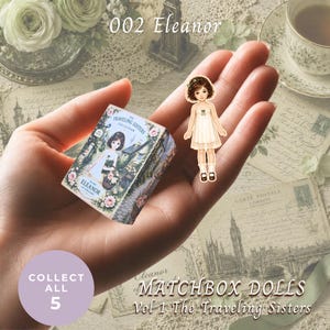 May include: A small rectangular matchbox featuring a floral design and the text "The Traveling Sisters Collection" and "Eleanor of England," accompanied by a die-cut paper doll figure wearing a white dress with a green bow and brown shoes.