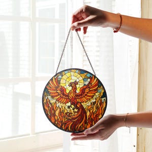 a hand holding a stained glass bird hanging from a chain