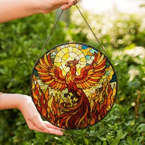 a hand holding a stained glass bird hanging from a chain