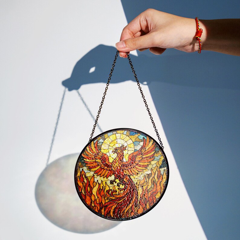 a hand holding a stained glass bird ornament