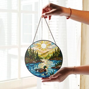 a hand holding a stained glass sun catcher