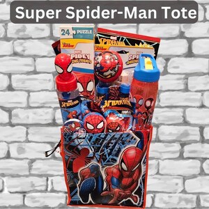 May include: A Spider-Man themed tote bag filled with toys and treats. The bag features Spider-Man graphics and the text "Super Spider-Man Tote". Contents include a puzzle, water bottles, and other Spider-Man themed items. The bag is red and blue.