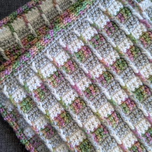May include: A crocheted fabric featuring a textured pattern of vertical ridges in white yarn, interspersed with blocks of variegated yarn in shades of green, pink, and grey. The textile displays a repeating grid-like structure with the text Clever Stitch Co.