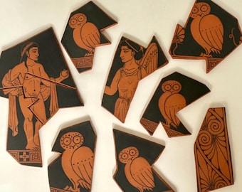 May include: Eight ceramic shards featuring black and terracotta-colored figures in a classical style. The pieces display illustrations of owls, a winged figure, a standing person draped in fabric, and decorative geometric patterns on a dark background.
