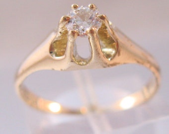 May include: A gold ring with a clear gemstone set in a unique, open-work design.