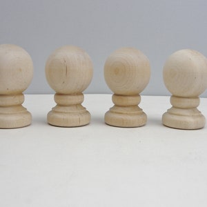 May include: Four wooden finials with a round top and a base with a decorative ring. The finials are all the same size and are made of light wood.