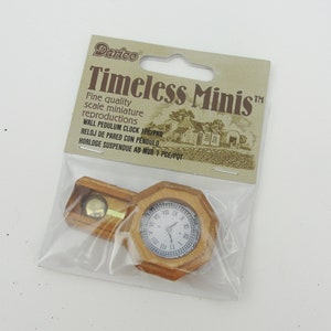 May include: A miniature wooden wall clock with a pendulum, packaged in a clear plastic bag. The packaging features the text "Timeless Minis" and "Darico".