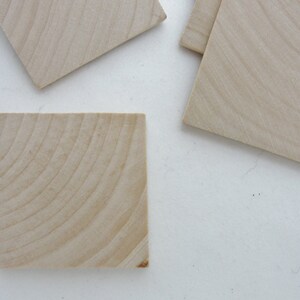 May include: A set of five unfinished wooden squares, perfect for crafting projects. The squares are made of light-colored wood with a natural grain pattern.