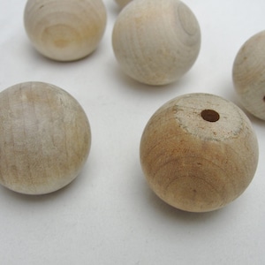 May include: Six unfinished wooden balls with a hole drilled through one of the balls.