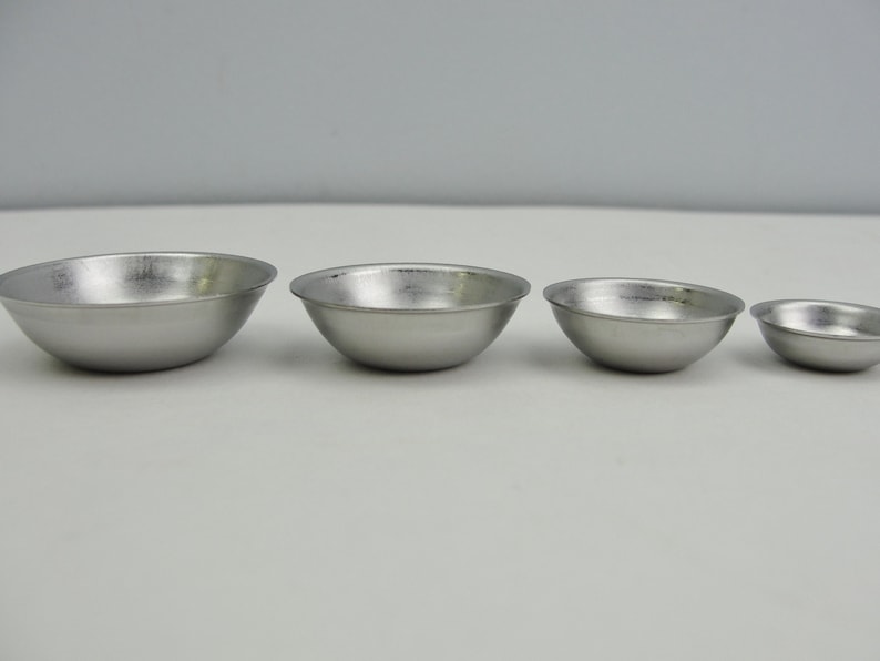 May include: Four silver metal bowls of varying sizes, arranged from largest to smallest.