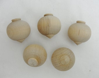 Peut inclure: Cinq toupies en bois non finies, chacune avec une pointe pointue. Les toupies sont rondes et ont une finition en bois naturel lisse.