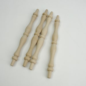 May include: Four unfinished wooden spindles with turned details. The spindles are approximately 10 inches long.