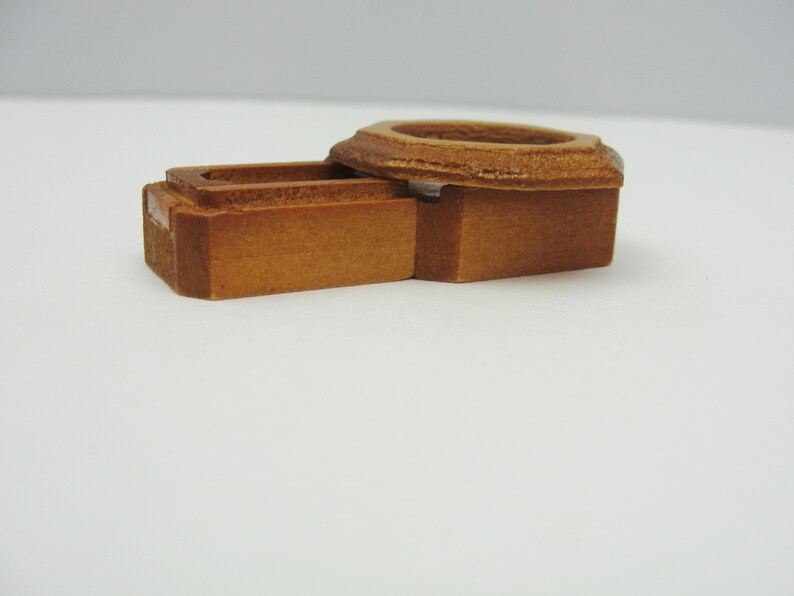 May include: A wooden box with a hinged lid. The box is made of light brown wood and has a simple design.