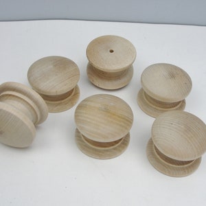 May include: Six unfinished wooden knobs with a round top and a slightly raised edge. The knobs are all the same size and shape.