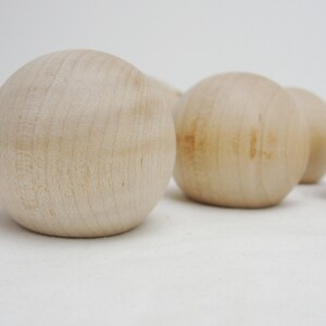 Puede incluir: Cinco bolas de madera lisas y redondas de color beige claro. Las bolas est&aacute;n dispuestas en fila, con la primera bola en primer plano y la &uacute;ltima bola en el fondo.