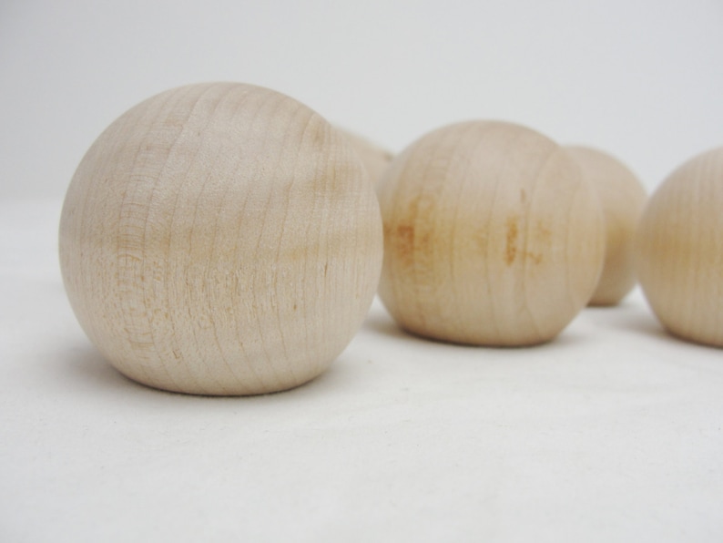 Puede incluir: Cinco bolas de madera lisas y redondas de color beige claro. Las bolas est&aacute;n dispuestas en fila, con la primera bola en primer plano y la &uacute;ltima bola en el fondo.
