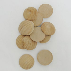 May include: A pile of round, wooden discs, all the same size and shape. The discs are a light brown color and have a smooth, polished finish.