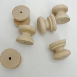 May include: Six unfinished wooden knobs with a round top and a smaller round base. The knobs have a hole in the center of the top.