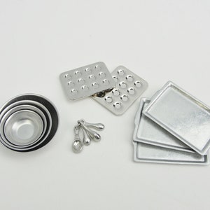 May include: A set of miniature silver baking tools, including four measuring spoons, a set of four nesting bowls, two muffin tins, and three baking sheets.