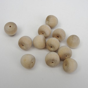 May include: A group of 12 natural wood round beads with a hole drilled through the center. The beads are approximately 1 inch in diameter.