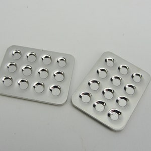May include: Two silver metal trays with 16 round indentations each. The trays are empty and have a shiny finish.