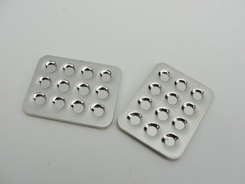 May include: Two silver metal trays with 16 round indentations each. The trays are empty and have a shiny finish.
