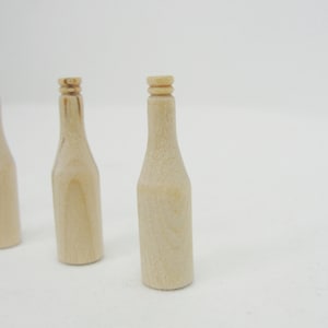 May include: Three wooden bottle shaped craft blanks. The blanks are unpainted and have a natural wood color.