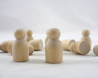 May include: A group of wooden figurines, each with a rounded head and a simple, cylindrical body. The figurines are made of unfinished wood and are arranged in a circle on a white surface.