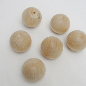 Puede incluir: Seis esferas de madera natural, cada una con una superficie lisa y ligeramente texturizada. Las esferas son todas del mismo tama&ntilde;o y est&aacute;n dispuestas en semic&iacute;rculo sobre un fondo blanco.