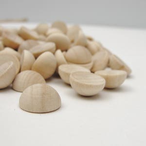 May include: A pile of unfinished, natural wood half-round circles. The circles are smooth and have a light brown color.
