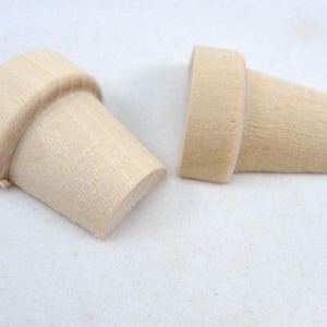 May include: Two unfinished wooden miniature flower pots. The pots are light brown and have a smooth, slightly textured surface.