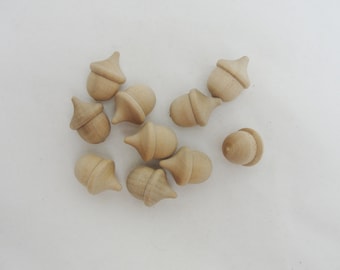 May include: A collection of 10 unfinished wooden acorn ornaments. The acorns are all the same size and shape, and they have a smooth, natural finish.