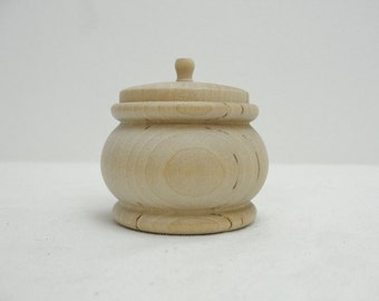 May include: A small, round, wooden box with a lid. The box is made of light-coloured wood and has a smooth finish.